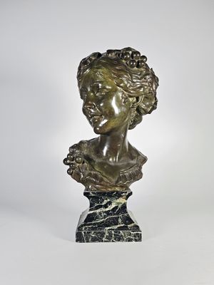 un buste antique en bronze représentant une femme aux cheveux bouclés, posé sur un socle en marbre