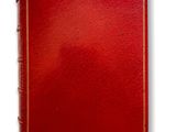 an old book with a red cover and gold trim