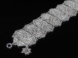 an image of a close up of a silver bracelet on a black surface