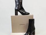 une paire de bottines en cuir noir posée sur une boîte