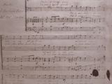 an old sheet of music sitting on top of a wooden table