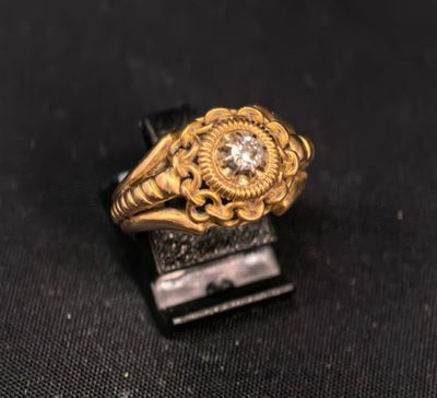 gros plan d'une bague en or et diamants sur une surface noire