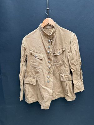 une veste beige suspendue à un cintre contre un mur bleu