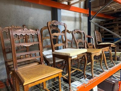 many wooden chairs and tables in a warehouse