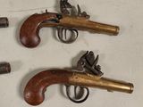 three antique pistols are displayed on a table with a white background