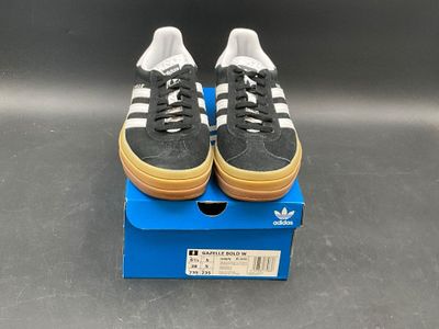 adidas superstar shoes in a box on a grey surface
