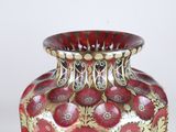 a red and gold vase sitting on a white surface