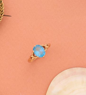 une image représentant une bague en or surmontée d'une pierre bleue