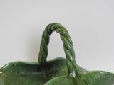 a green basket with a handle on a white table