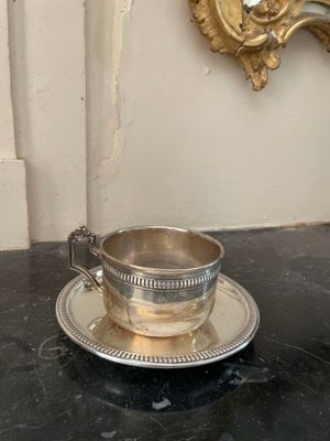 une tasse et une soucoupe argentées posées sur une table noire