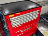 une armoire à outils rouge avec un dessus noir, dans un garage