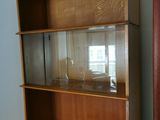 a wooden bookcase with a glass door in the corner