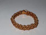 gold plated bracelet on white surface with a wooden bead