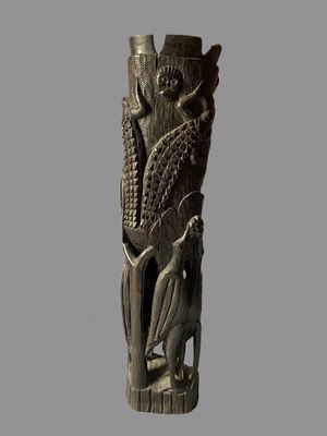 a wooden carving of a man and a bird on a tree stump