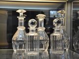 five clear glass bottles sitting on a glass shelf