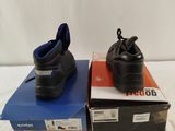 two pairs of black shoes sitting on top of boxes on a white surface