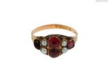 un gros plan d'une bague en or sertie d'une pierre rouge et de perles