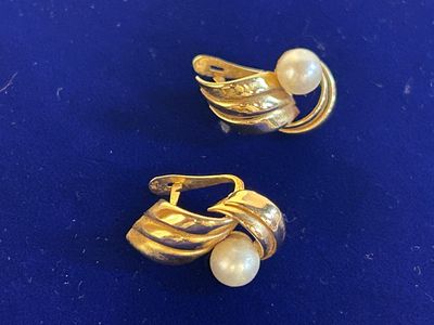 pair of gold tone earrings with pearls on a blue surface