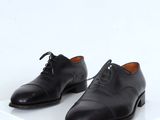 black leather shoes with laces on a white surface
