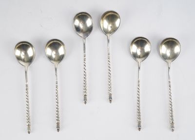 six cuillères en argent sont alignées sur une surface blanche