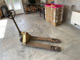 a fork lifter in a garage with a pile of wood in the background