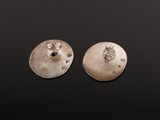 a pair of silver earrings on a black surface