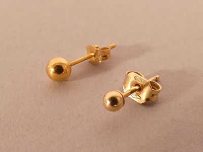 two pairs of gold stud earrings sitting on top of a table