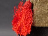 a close up of a hat with a red tassel on it
