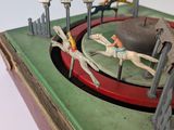 toy figurines of horses and jockeys in a ring on a table