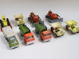 six camions miniatures alignés sur une surface blanche