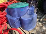 a blue water tank with a green lid and a red hose