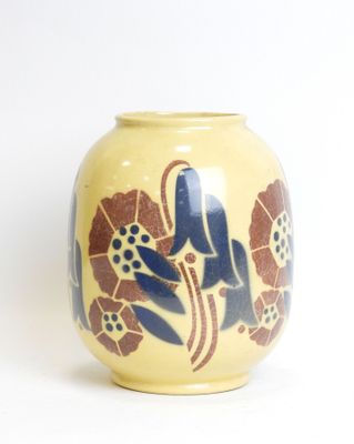 a yellow vase with blue flowers on it on a white surface