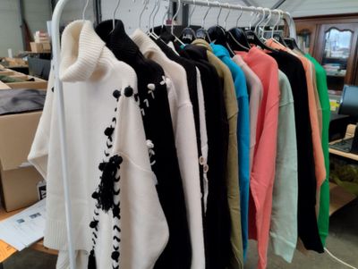 a lot of sweaters hanging on a rack in a room