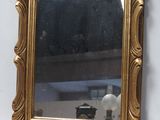 un miroir avec un cadre doré sur un mur blanc