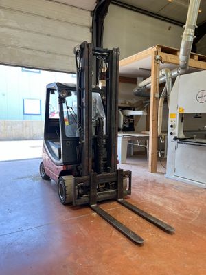 un chariot élévateur dans un entrepôt, avec une machine en arrière-plan