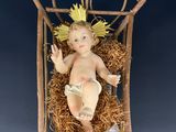figurine représentant l'Enfant Jésus dans une crèche surmontée d'une croix