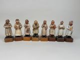 Plusieurs figurines représentant des personnes sont alignées sur des blocs de bois