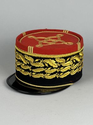 un chapeau rouge et doré posé sur une assiette noire