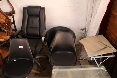 trois fauteuils en cuir noir et une table en verre dans une pièce