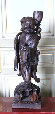 une statue représentant une personne tenant un éventail, posée sur une table rouge