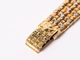 a close up of a gold bracelet on a white surface