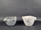 two white and gray bowls sitting next to each other on a black surface