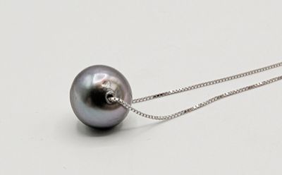 une perle noire suspendue à une chaîne en argent sur un fond blanc