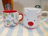 two starbucks mugs sitting on a table with a cup in the background