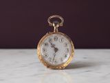 une montre de poche en or posée sur une table en marbre