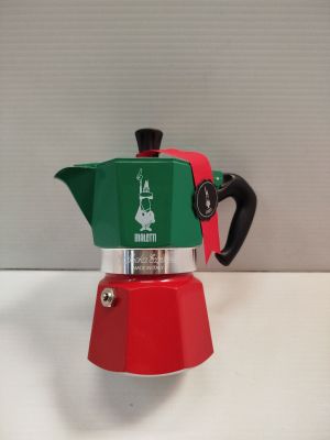 une cafetière rouge et verte posée sur une table blanche