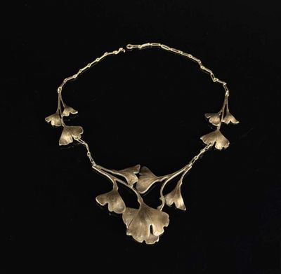 a gold necklace with leaves and flowers on a black background