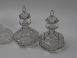 three clear glass bottles with lids and lids on a white surface