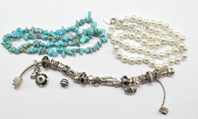 deux colliers ornés de perles et de breloques sur un fond blanc