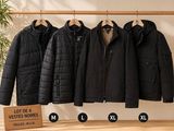 quatre vestes suspendues à un portant dans un magasin de vêtements